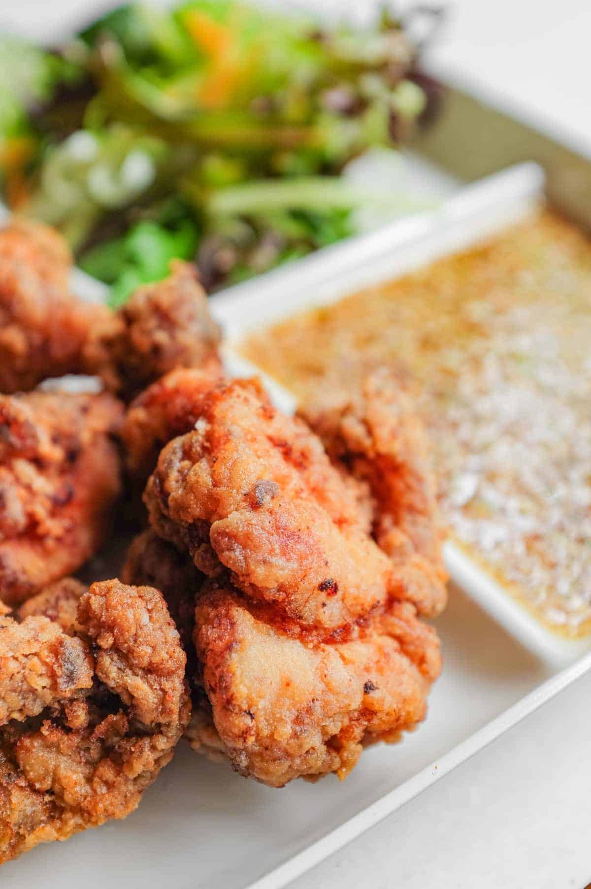 A close up of karaage chicken alongside salad and yurinchi sauce