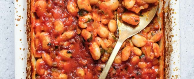 Greek gigantes plaki butter beans baked in tomato sauce in ceramic dish.