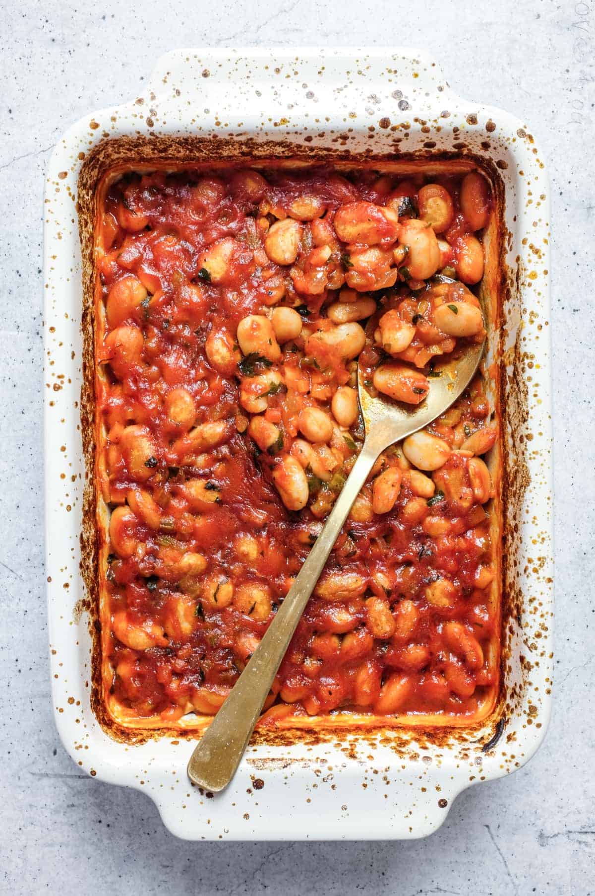 Greek gigantes plaki butter beans baked in tomato sauce in ceramic dish.