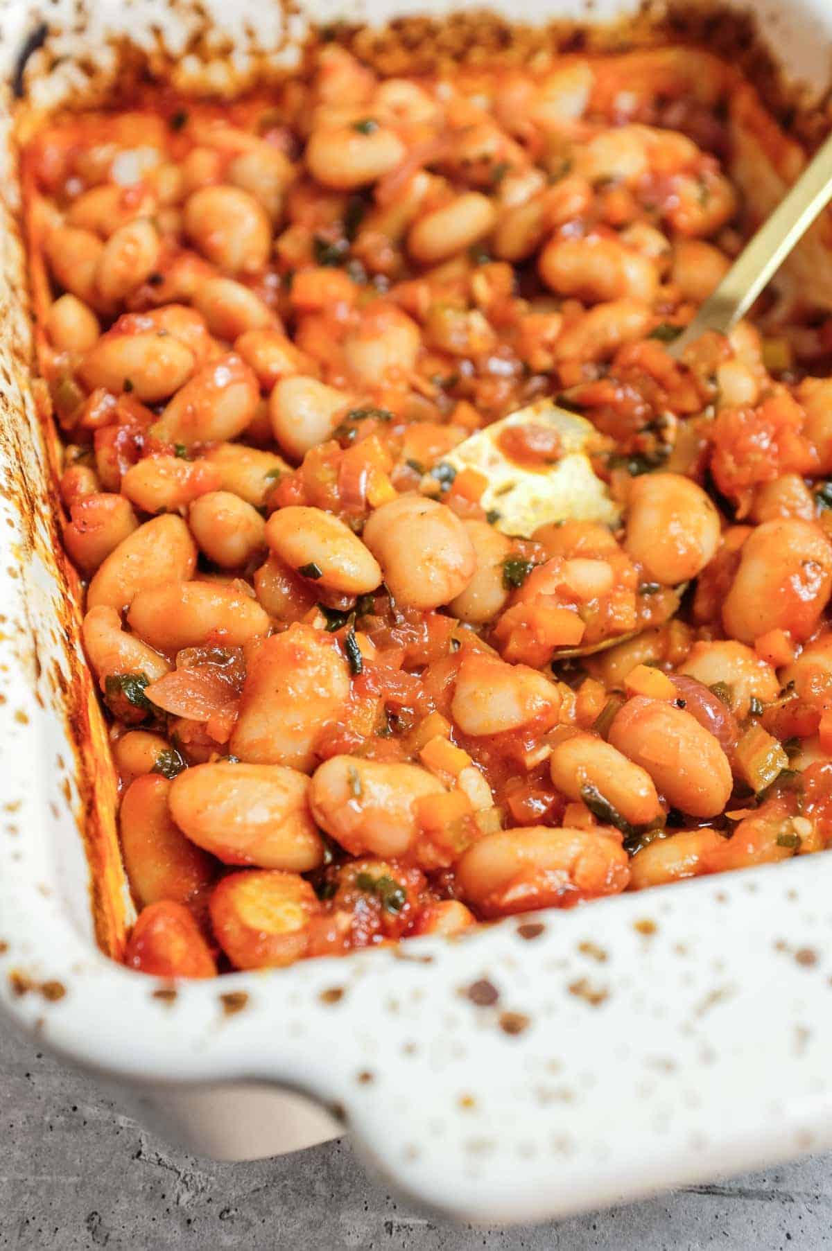 Oven baked gigantes plaki greek butter beans in ceramic dish.