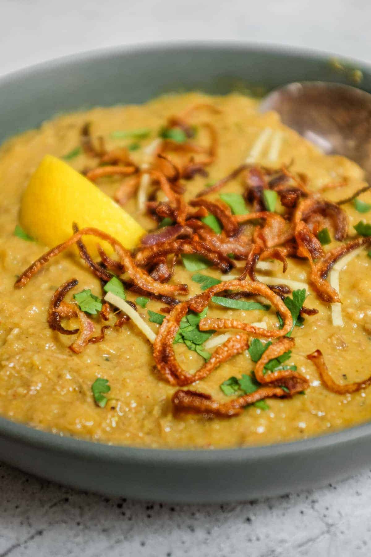 Indian haleem served hot with crispy onions and fresh herb topping