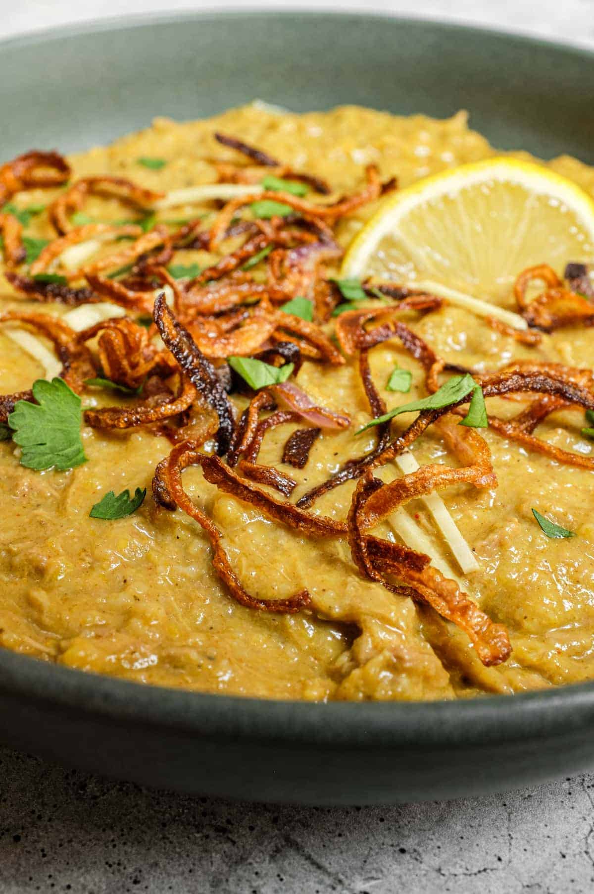 Comforting haleem dish garnished with cilantro, mint and lemon
