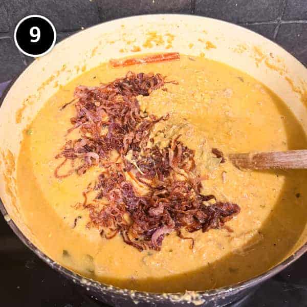Hyderabadi Haleem (Lamb & Lentil Stew) | cookeatworld.com fried onions are added to a large pot of bubbling Hyderabadi haleem.