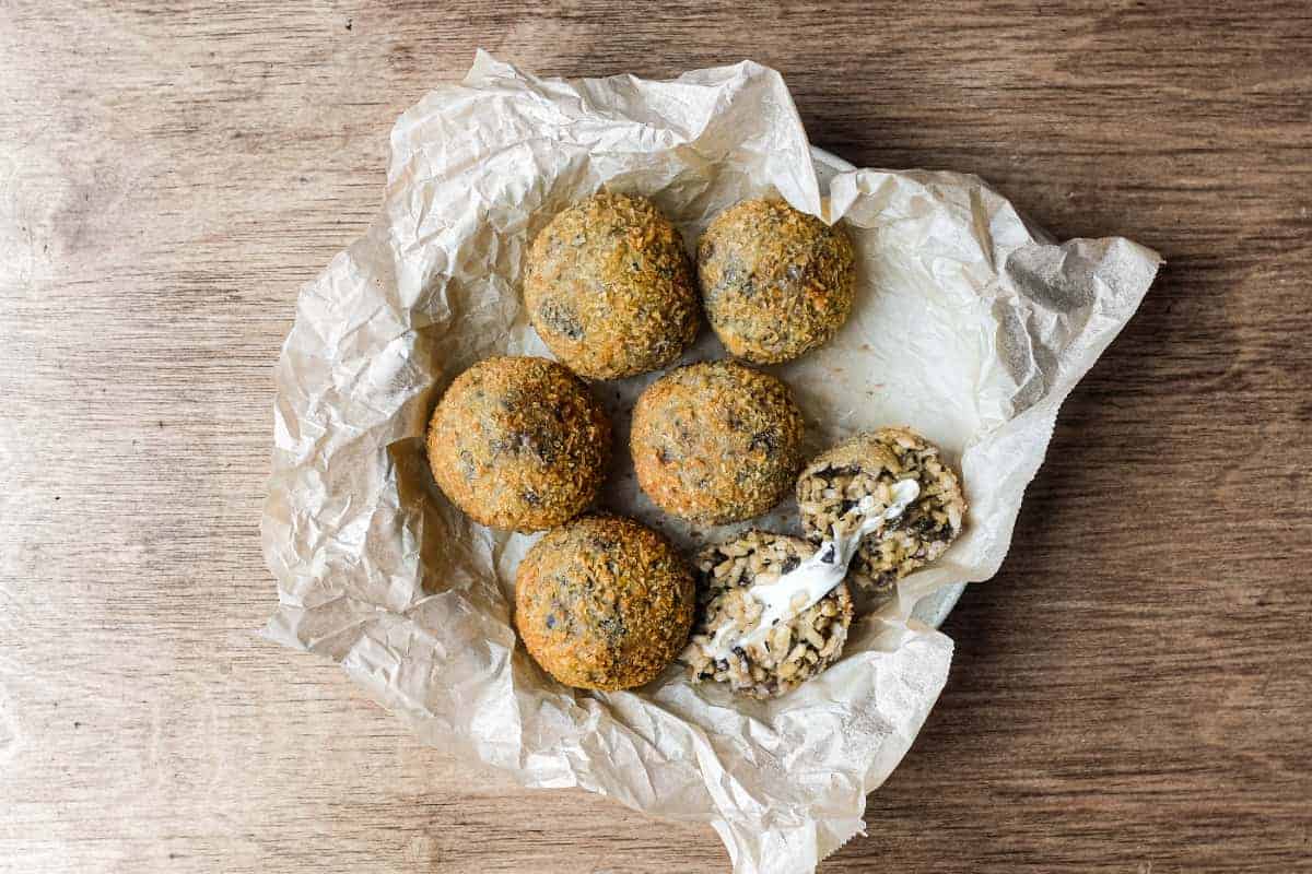 Golden fried mushroom arancini with panko breadcrumb coating on a serving platter.
