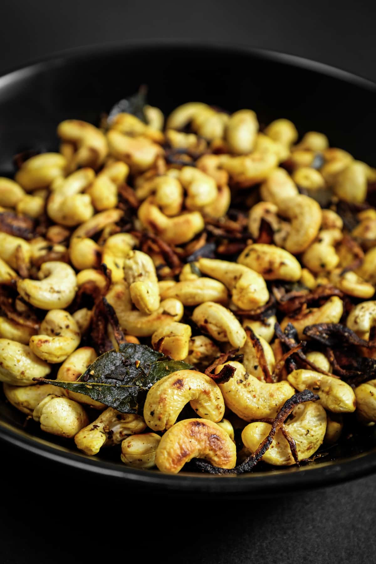 Bowl of spicy cashew nuts with curry leaves and chilli, inspired by South Indian flavours.