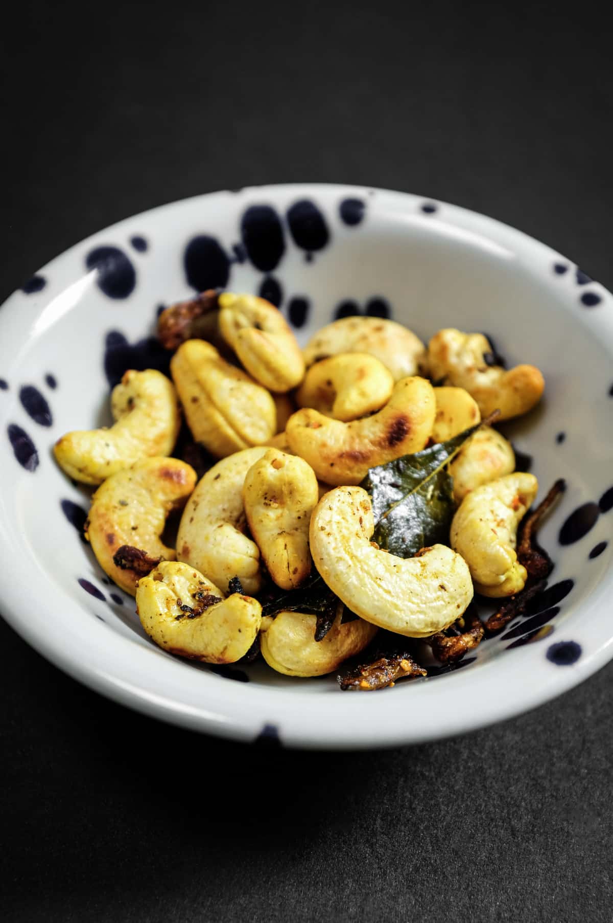 Bowl of crunchy cashews with curry leaves, chilli and aromatic spices.