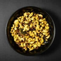 Bowl of crunchy cashews with curry leaves, chilli and aromatic spices.