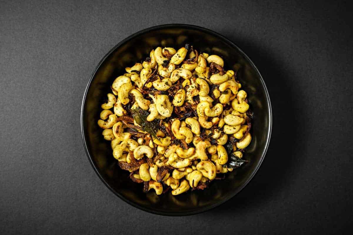 Bowl of crunchy cashews with curry leaves, chilli and aromatic spices.