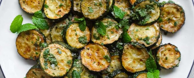 A serving platter of zucchini alla scapece with golden fried zucchini slices marinated in mint, garlic and white wine vinegar.