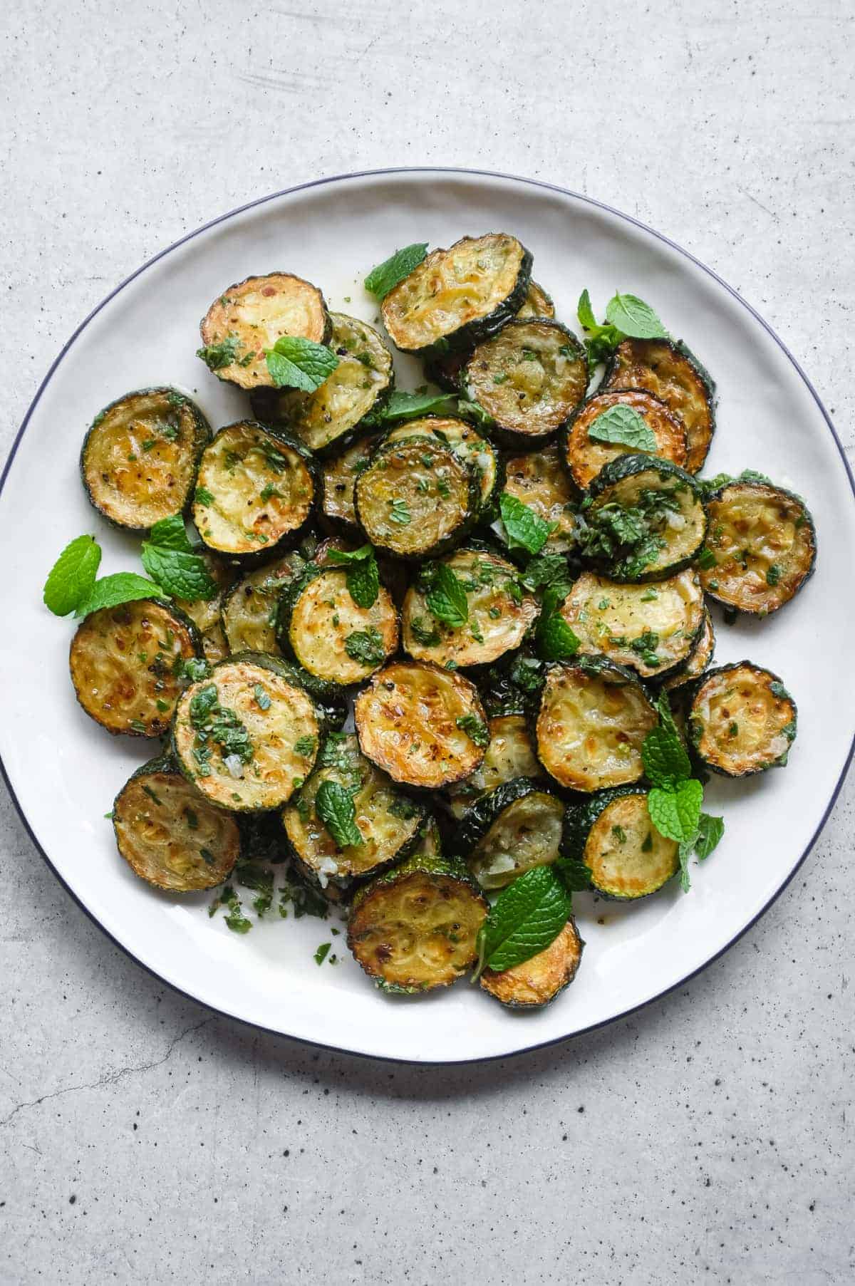 A serving platter of zucchini alla scapece with golden fried zucchini slices marinated in mint, garlic and white wine vinegar.