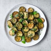 A serving platter of zucchini alla scapece with golden fried zucchini slices marinated in mint, garlic and white wine vinegar.