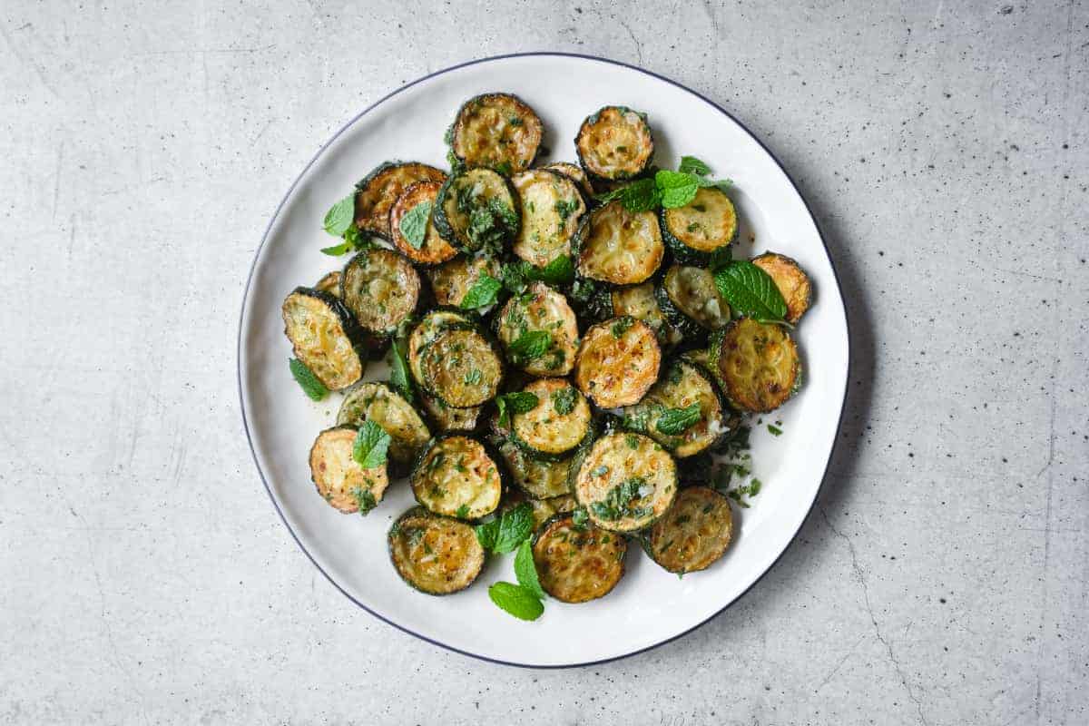 A serving platter of zucchini alla scapece with golden fried zucchini slices marinated in mint, garlic and white wine vinegar.