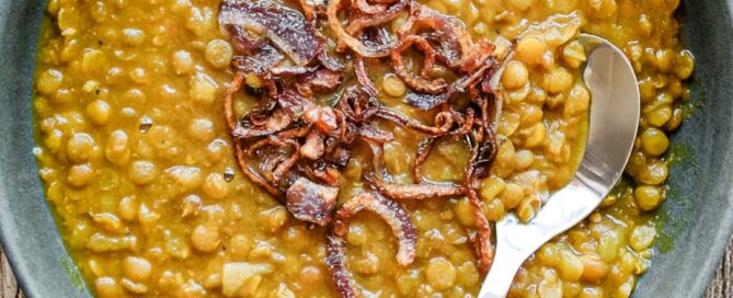 Creamy Iranian adasi with whole lentils and golden onion garnish