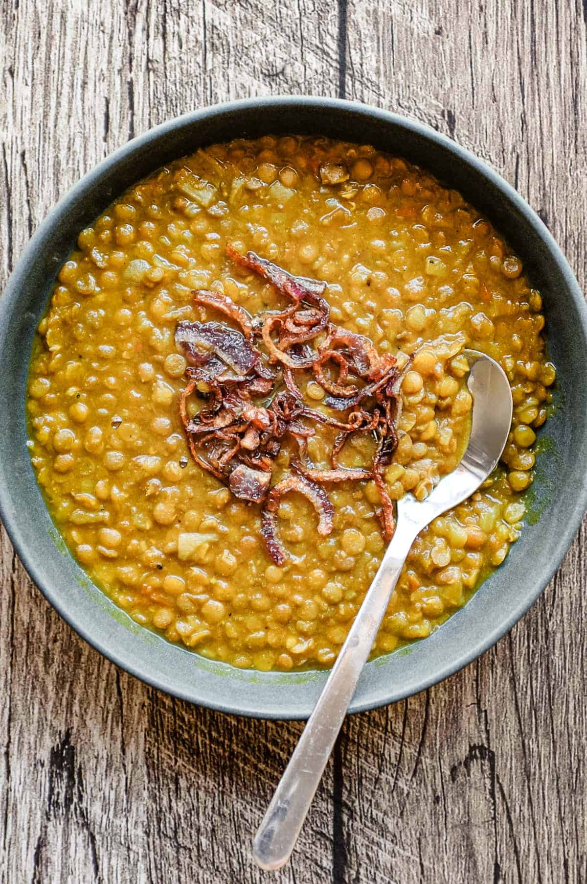 Creamy Iranian adasi with whole lentils and golden onion garnish