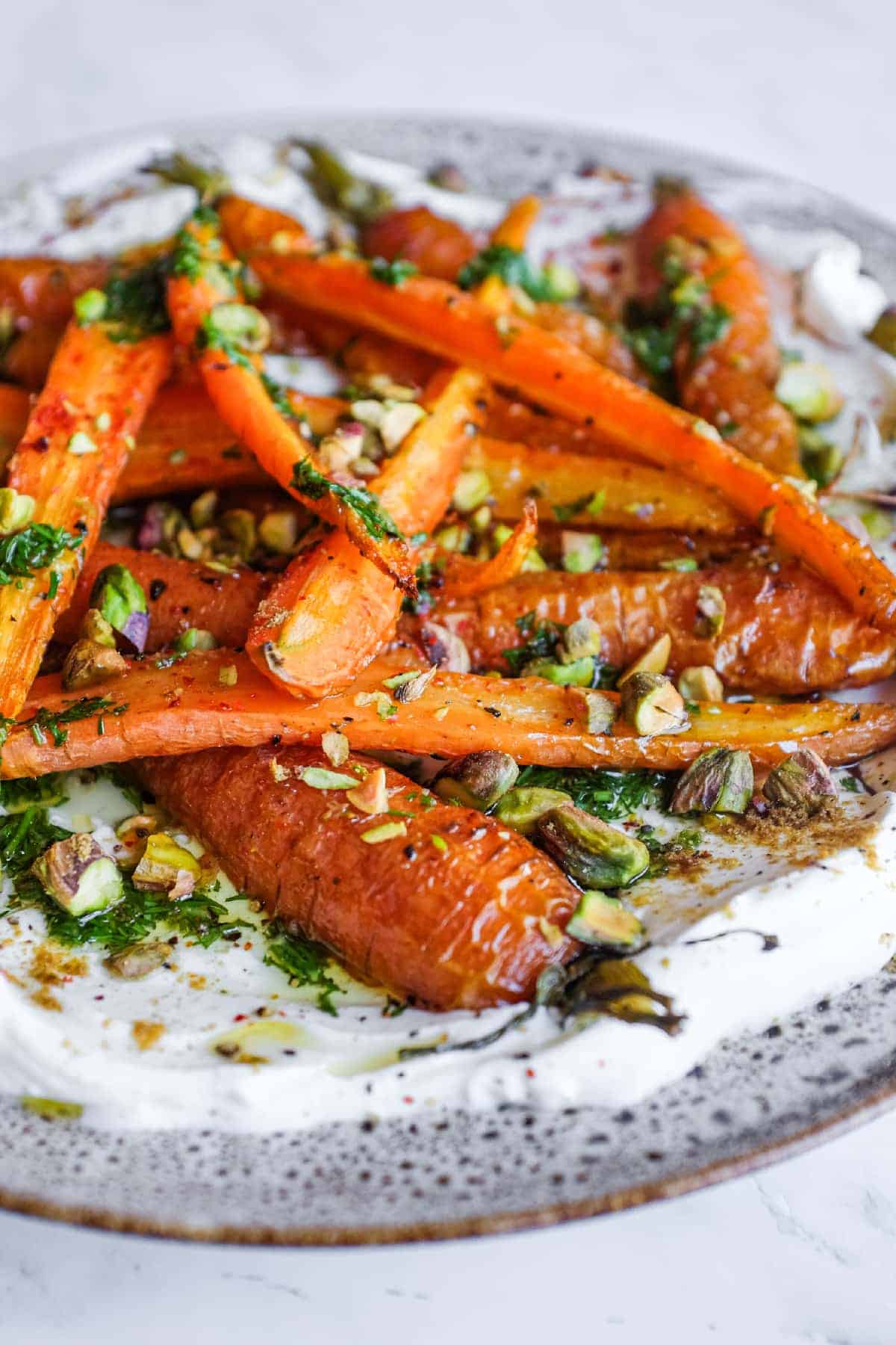 A platter of roast carrots with labneh topped with crunchy pistachios, dill and a sprinkle of cumin.