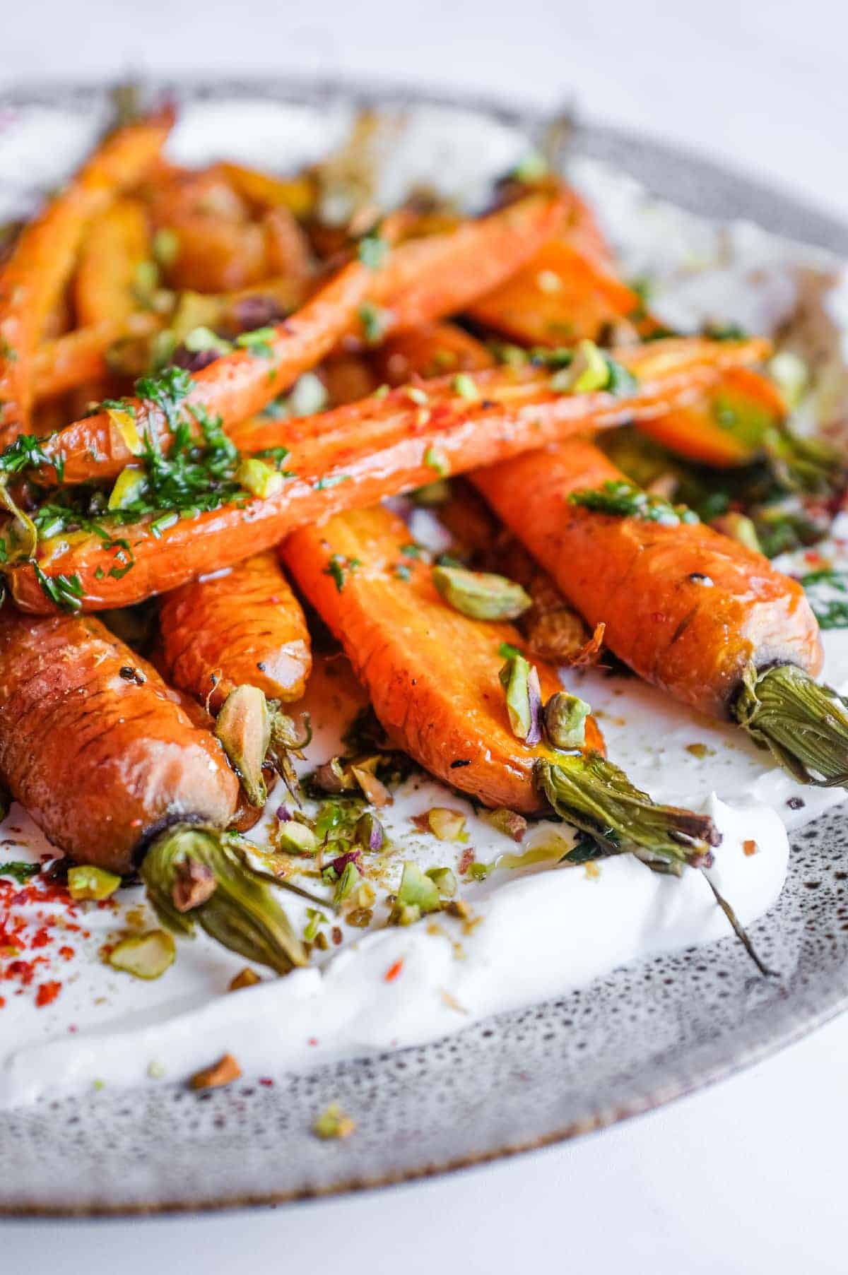 Colourful roasted carrots with labneh and pistachios served as part of a Middle Eastern mezze spread.