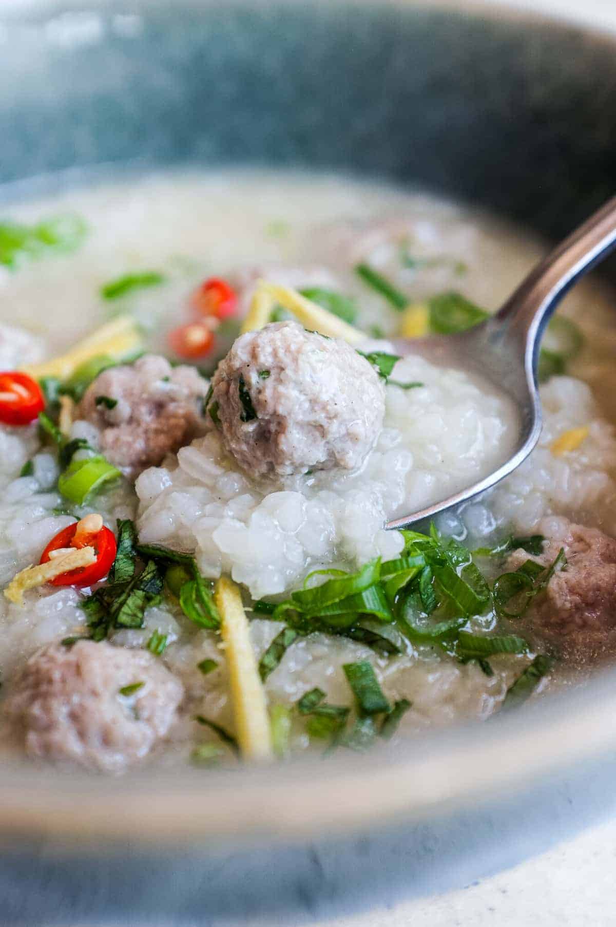 Homemade Thai pork and rice soup served hot with coriander leaves, ginger, chillies and sliced spring onions