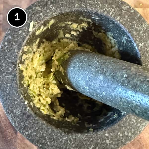 Garlic, coriander stems and spring onion whites prepared in a pestle and mortar for the aromatic soup base
