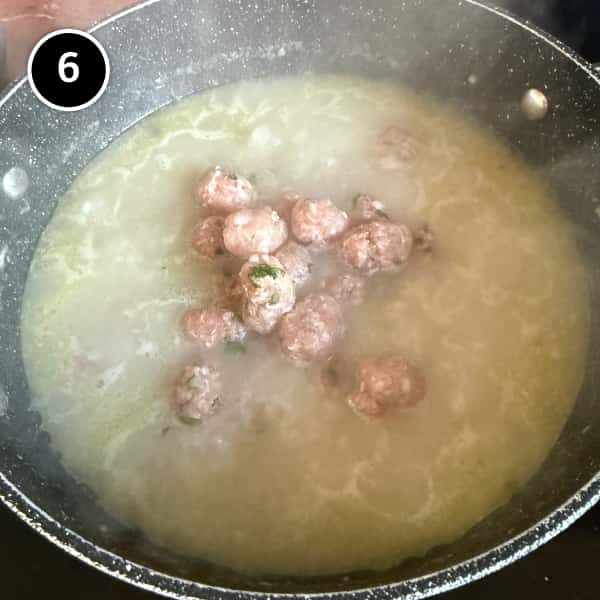Pork meatballs simmering in fragrant Thai rice soup until fully cooked