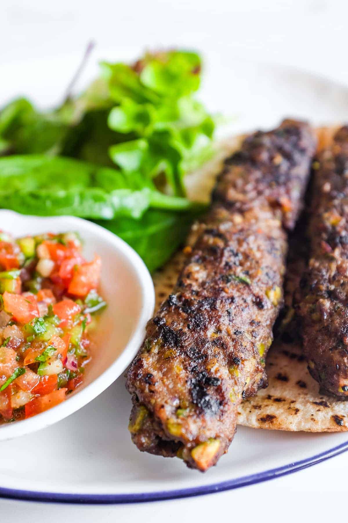 Grilled Turkish köfte kebabs made with lamb mince and pistachios ready to serve.