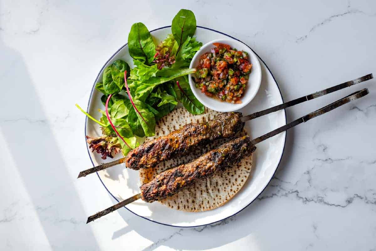 Tender Turkish lamb kebabs with pistachios served alongside a colourful spoon salad.