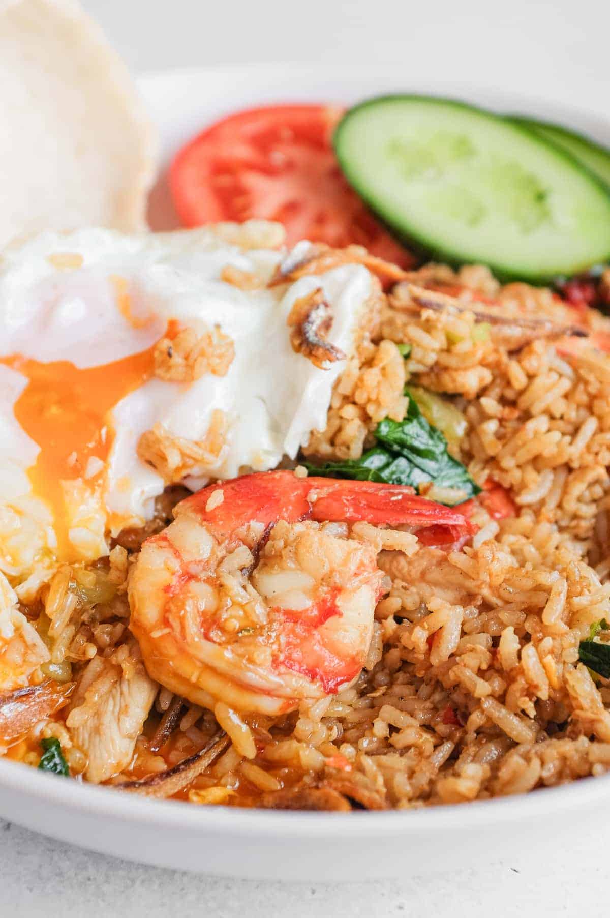 Bowl of spicy Malaysian fried rice with chicken, prawns and fried egg