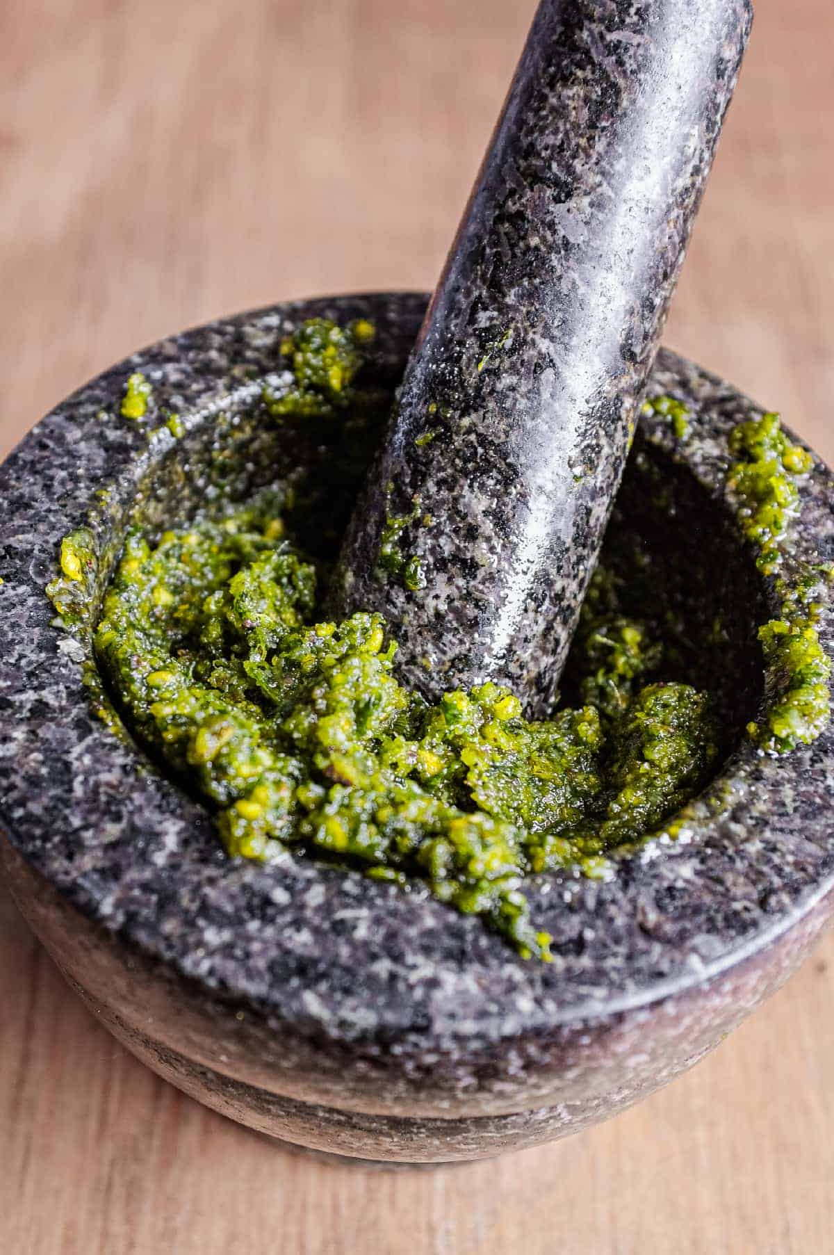 A pestle and mortar with a crushed pistachio pesto