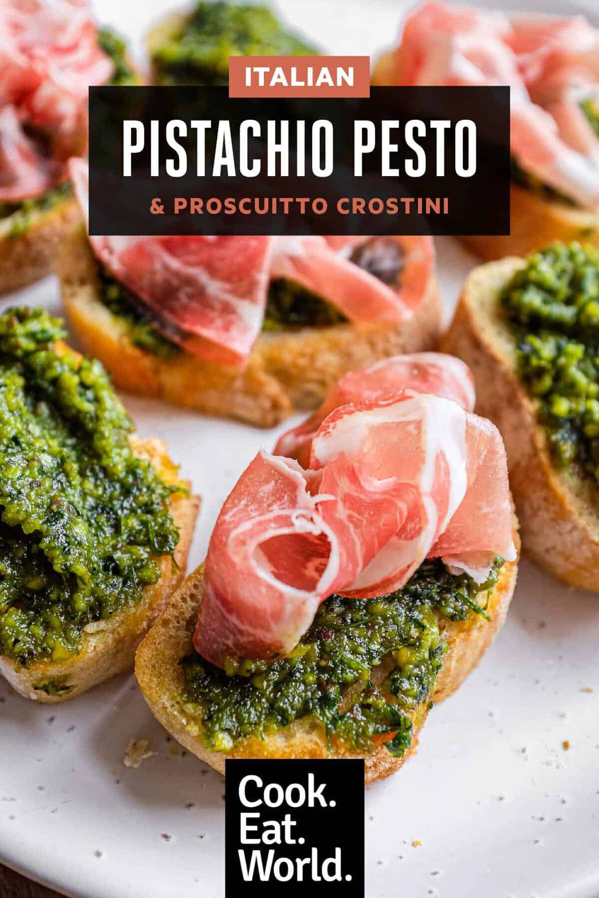 Close-up of authentic Sicilian pistachio pesto crostini garnished with prosciutto on half the slices.