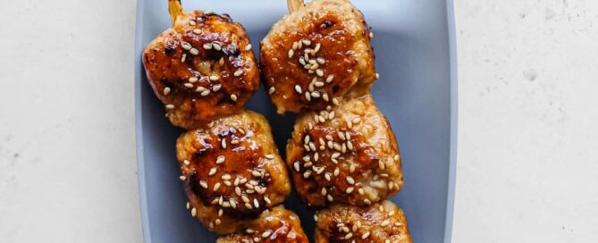 Japanese tsukune chicken meatball skewers glazed with tare and sprinkled with toasted sesame seeds