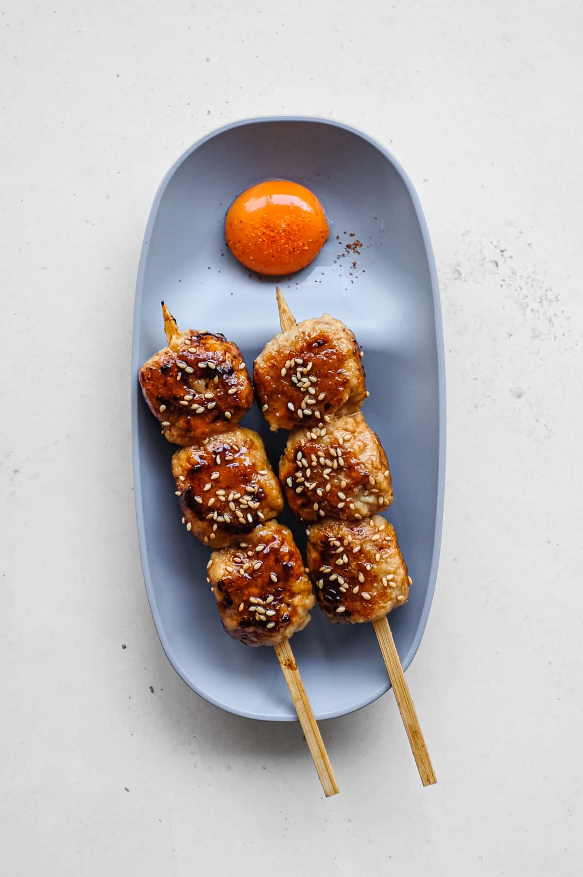 Japanese tsukune chicken meatball skewers glazed with tare and sprinkled with toasted sesame seeds