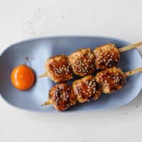 Japanese tsukune chicken meatball skewers glazed with tare and sprinkled with toasted sesame seeds
