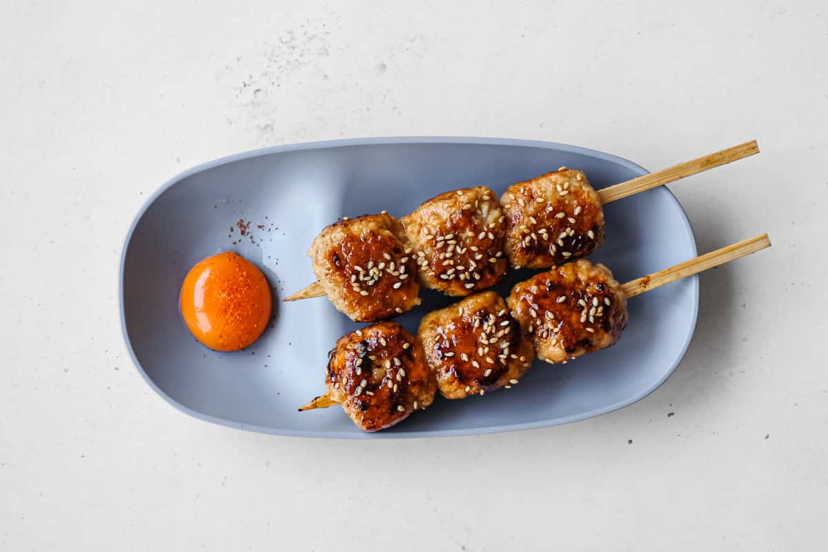 Japanese tsukune chicken meatball skewers glazed with tare and sprinkled with toasted sesame seeds