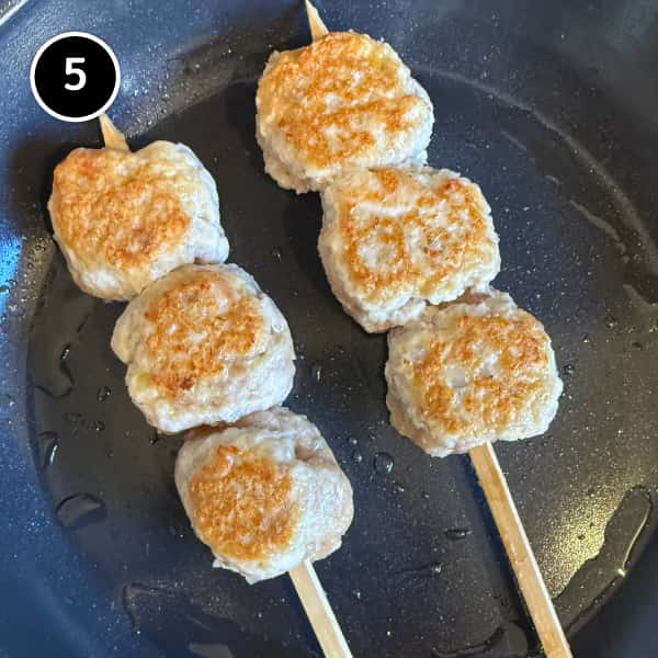 Tsukune (Japanese Chicken Meatballs) | cookeatworld.com Tsukune cooking in a lightly oiled frying pan until golden brown
