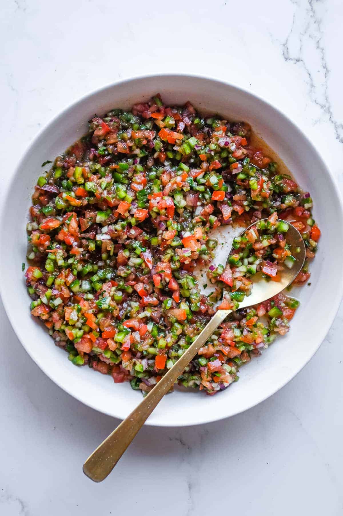 A bowl of authentic Turkish Spoon Salad with finely diced tomatoes, cucumber, onion and parsley in a tangy pomegranate dressing.
