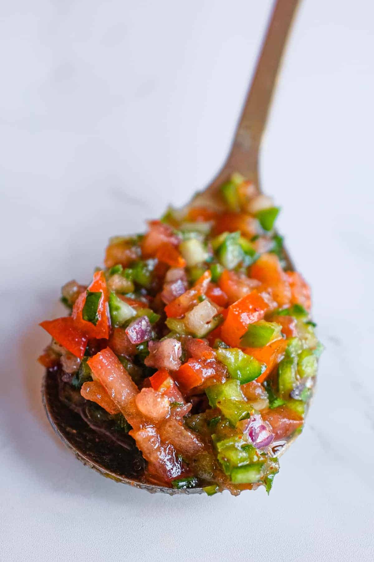 Close up of Turkish Spoon Salad with tomatoes, cucumber, peppers and parsley, finely diced and ready to serve.