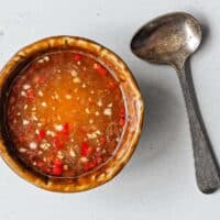 Freshly chopped garlic and red chilli in Vietnamese dipping sauce with a small spoon alongside