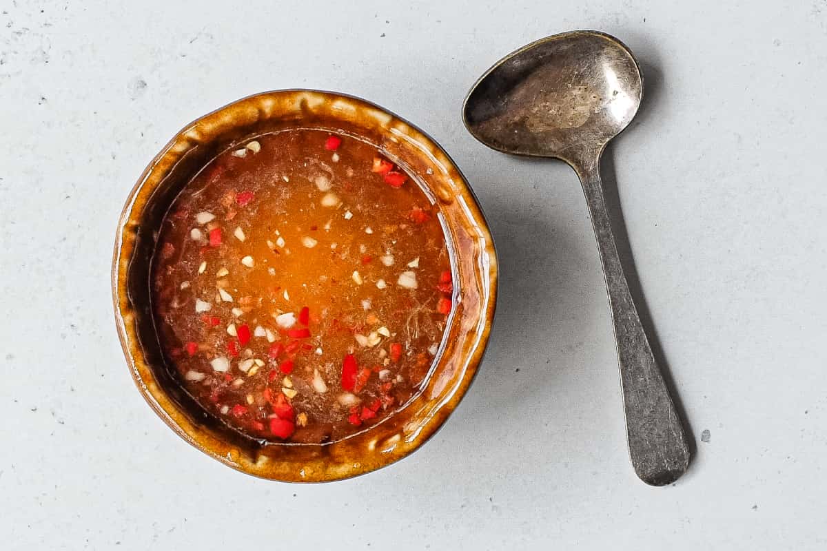 Freshly chopped garlic and red chilli in Vietnamese dipping sauce with a small spoon alongside