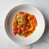 Overhead view of pollo alla romana with chicken, peppers, tomatoes and capers.