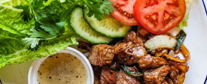 Vietnamese shaking beef served with lettuce, tomato, cucumber and fresh herbs