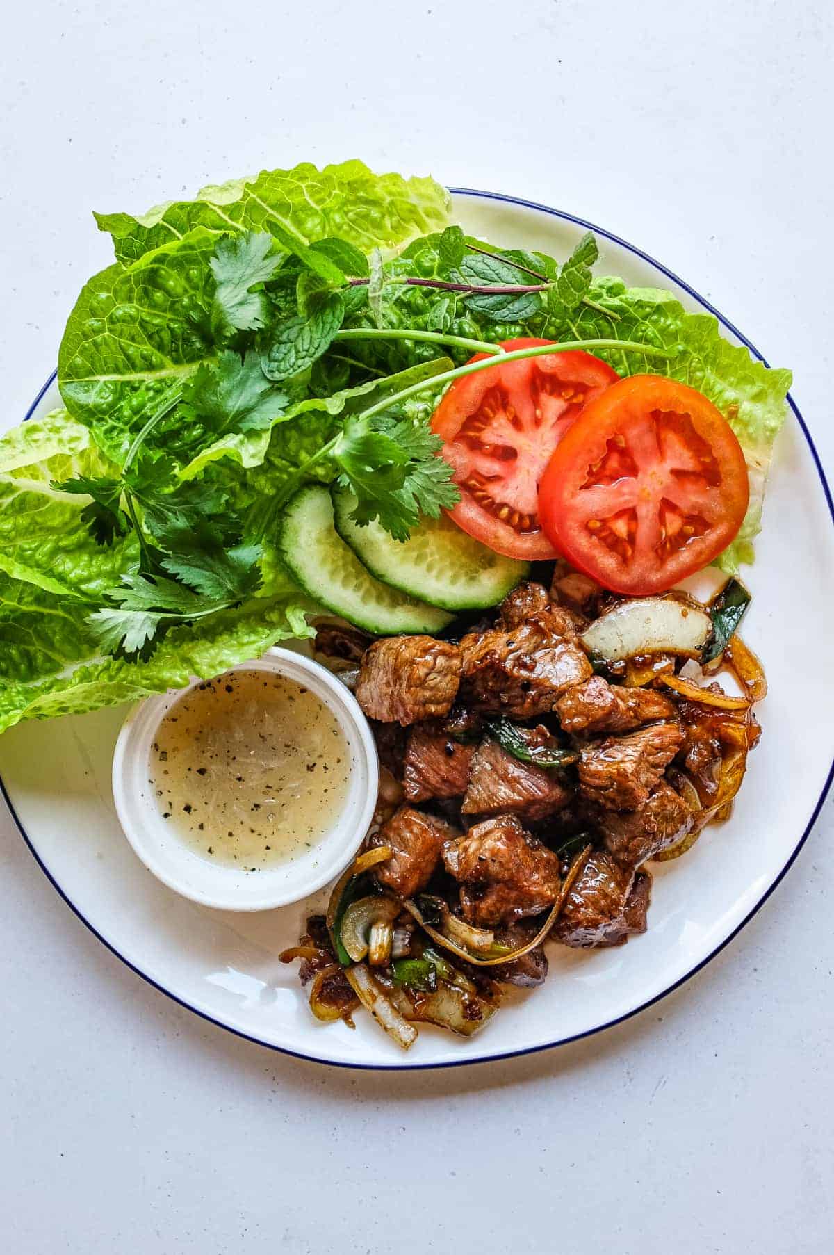 Vietnamese shaking beef served with lettuce, tomato, cucumber and fresh herbs