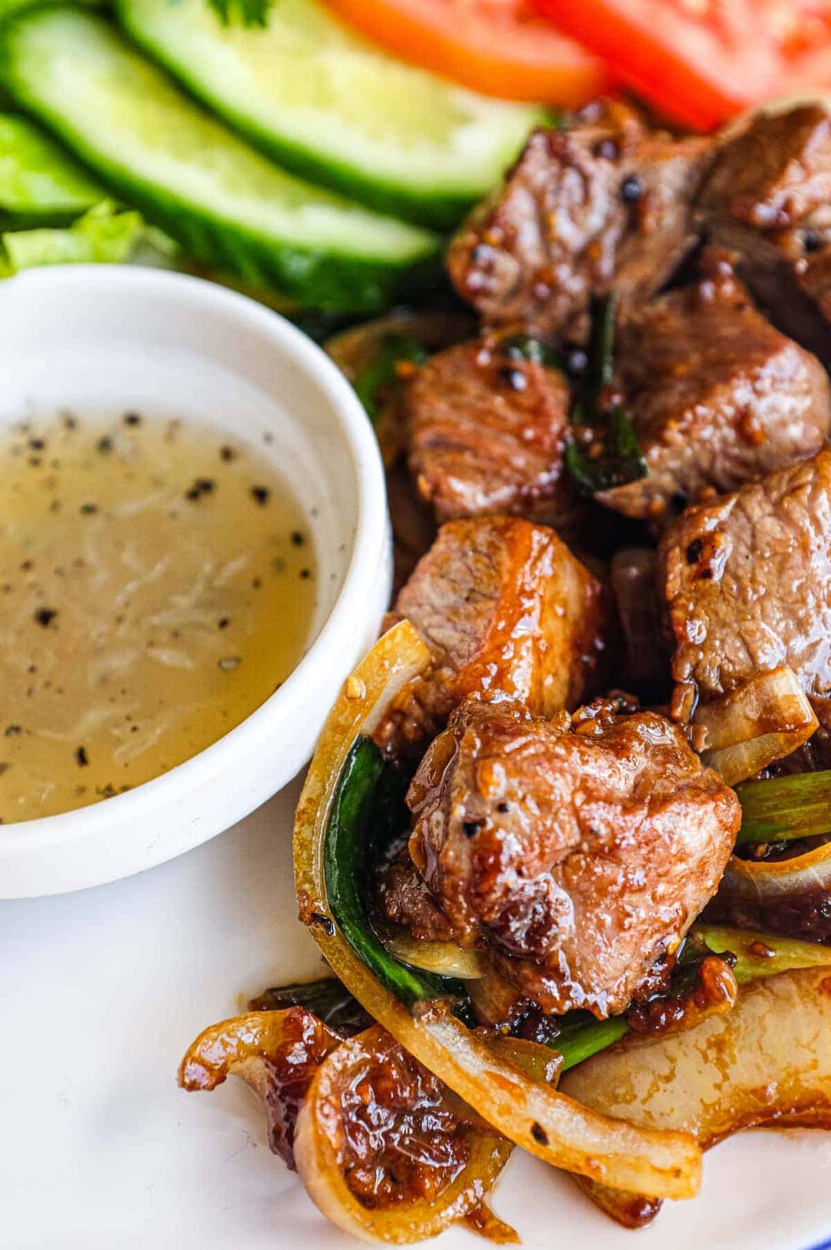 Vietnamese shaking beef served with lettuce, tomato, cucumber and fresh herbs