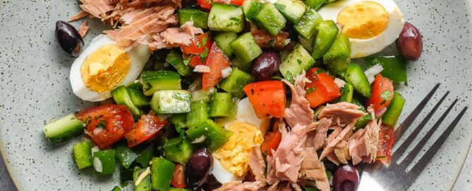Tunisian salad with chopped vegetables, tuna, boiled eggs and green olives on a serving platter