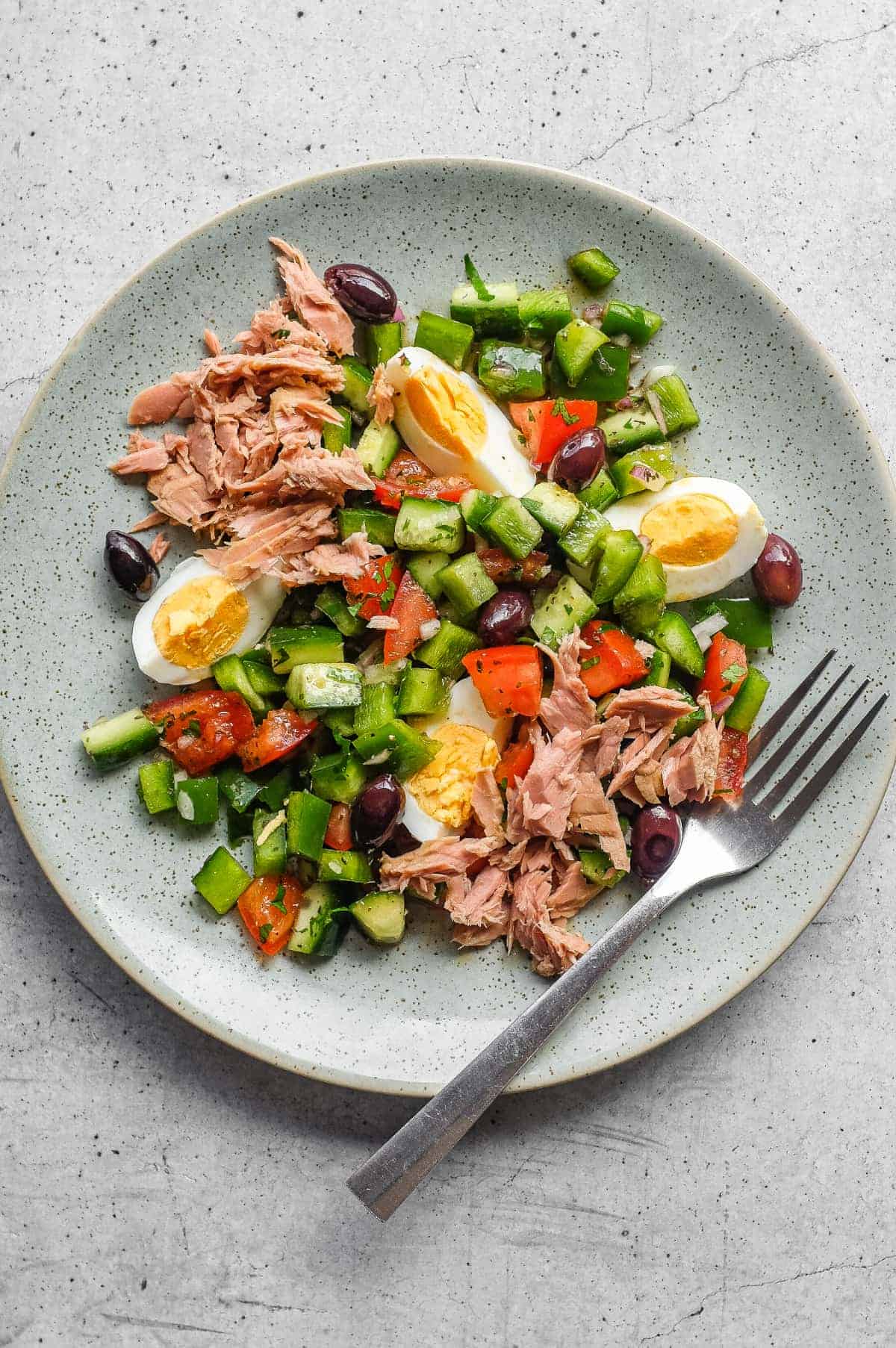 Tunisian salad with chopped vegetables, tuna, boiled eggs and green olives on a serving platter