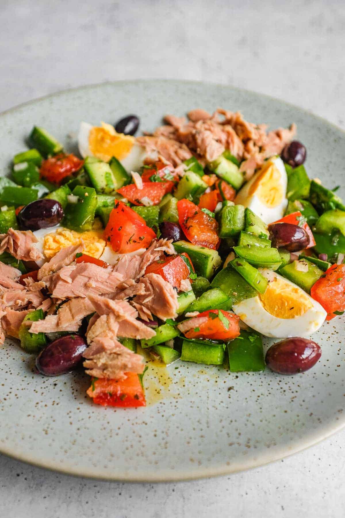Colourful Tunisian chopped salad garnished with flaky tuna, quartered eggs and olives
