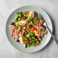 Tunisian salad with chopped vegetables, tuna, boiled eggs and green olives on a serving platter