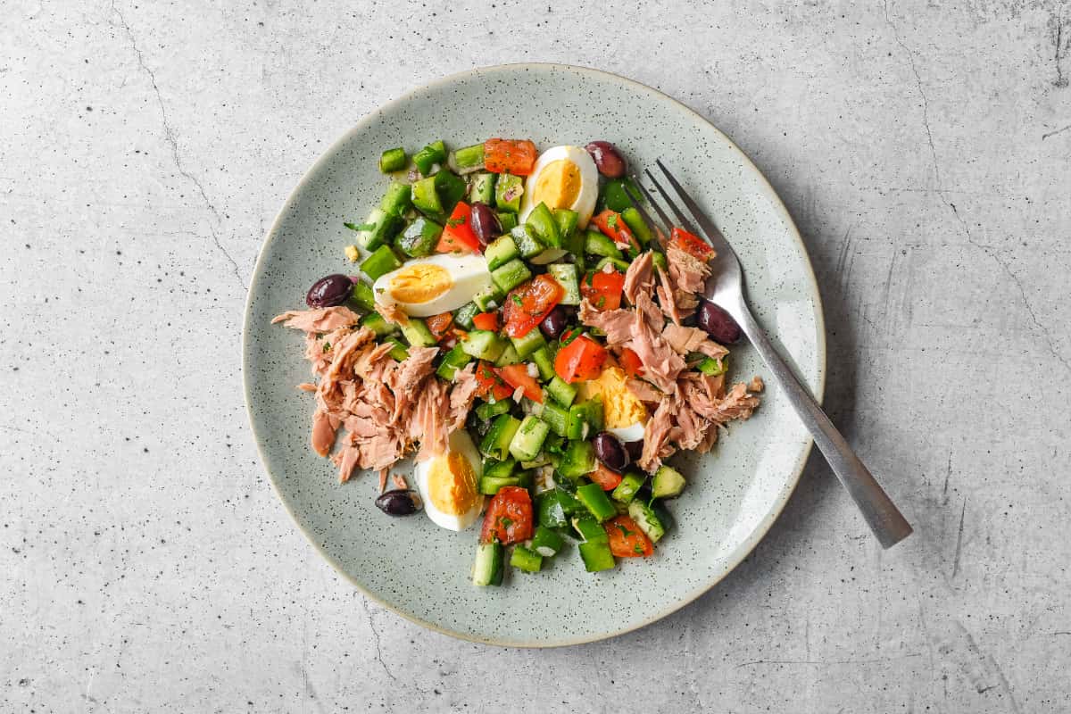 Tunisian salad with chopped vegetables, tuna, boiled eggs and green olives on a serving platter