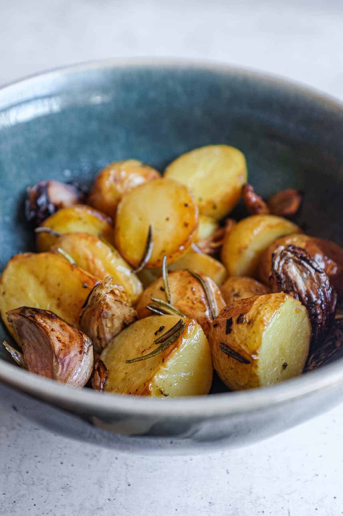 Close-up view of golden potatoes roasted with fresh rosemary and white wine.